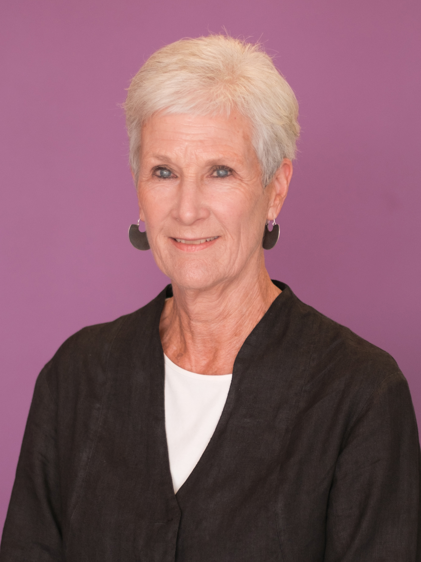 Annette smiles at the camera in front of a purple background