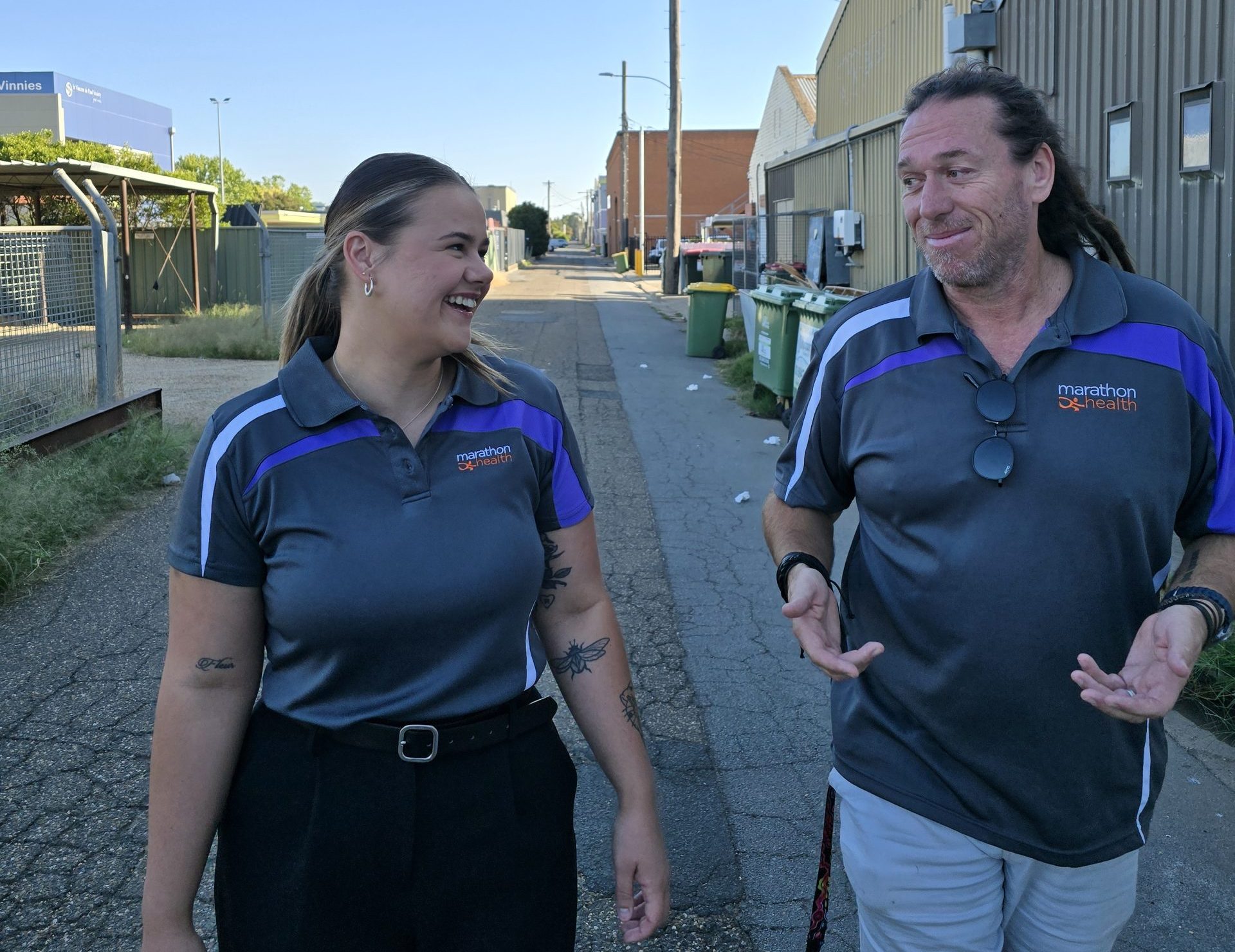 Homelessness Health Support Team Program team members smiling and walking down a laneway wearing Marathon Health uniform