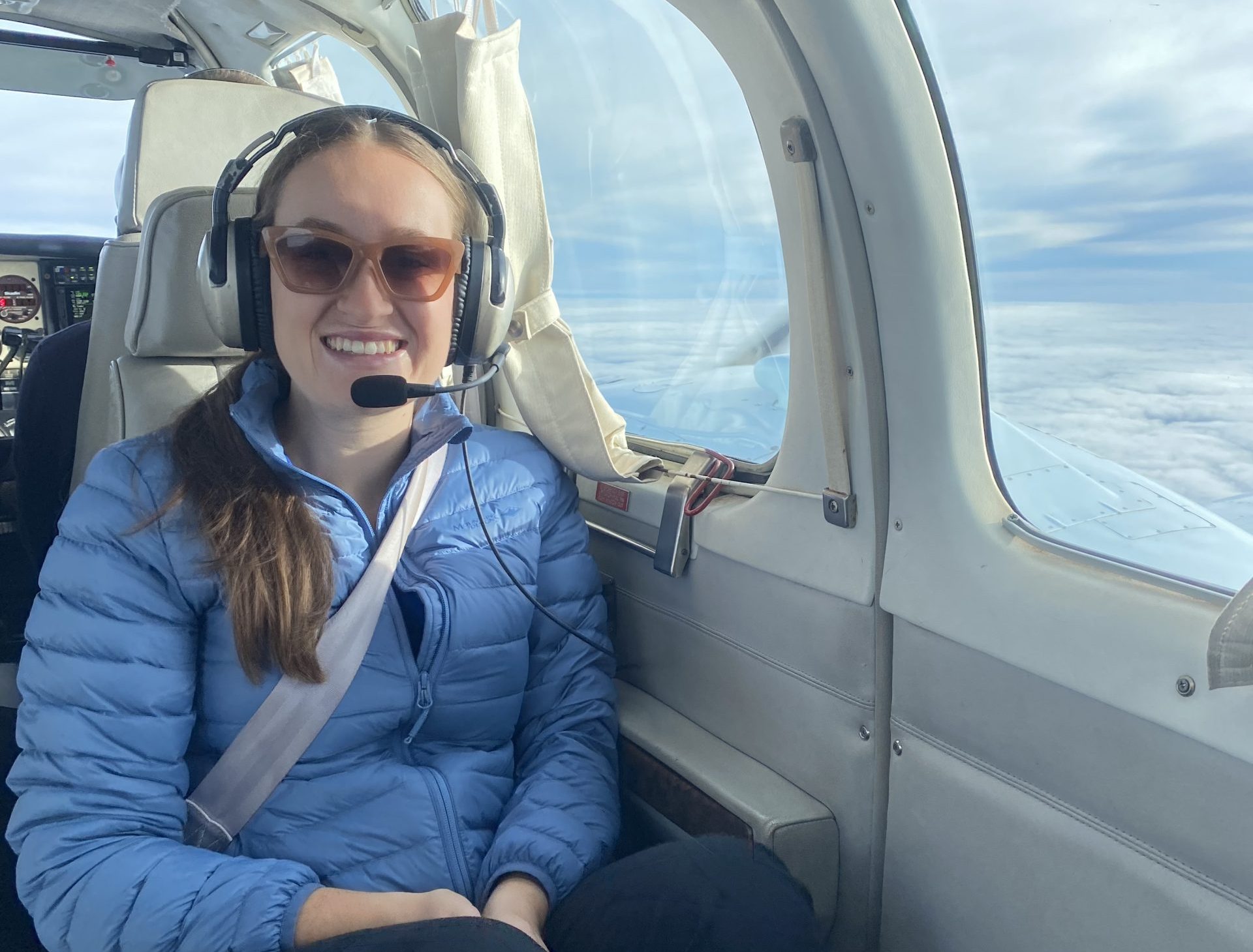 Ella sits in the light plane and smiles to camera as she flies to Bourke.